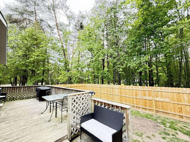 116 1st St, Hubbard Lake, MI 49747 - deck with outdoor dining space and view of scattered trees