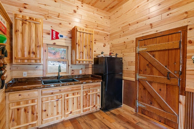 5997 Prospect St, Indian River, MI 49749 - kitchen with freestanding refrigerator, a sink, wooden walls, light wood finished floors, and dark stone countertops