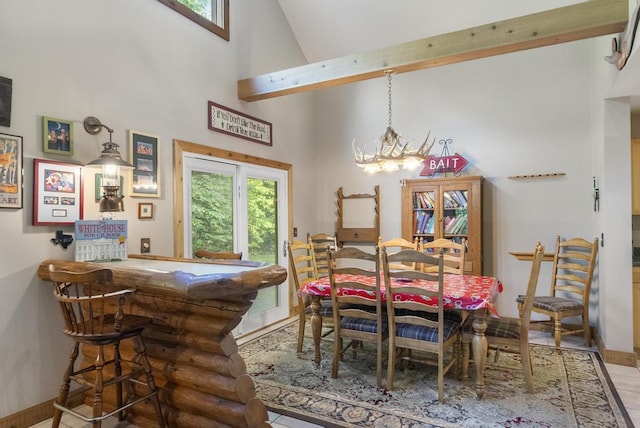 2715 Indian Rd, Brutus, MI 49716 - dining area featuring high vaulted ceiling, plenty of natural light, a chandelier, and a bar