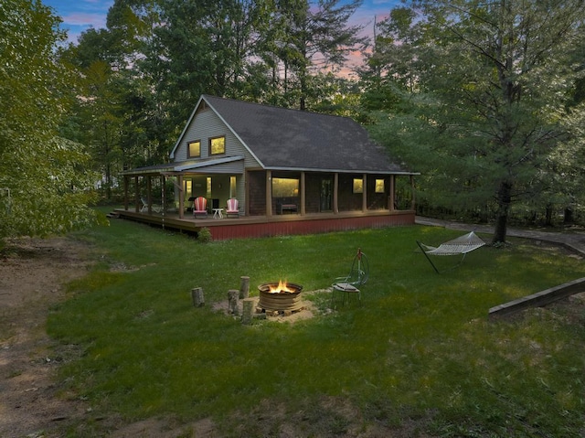 2715 Indian Rd, Brutus, MI 49716 - rear view of house with a fire pit, covered porch, a yard, and roof with shingles