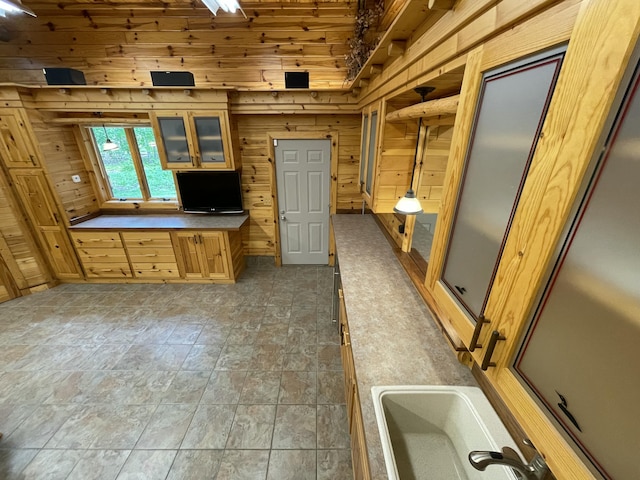 164 Invitational Dr, Gaylord, MI 49735 - kitchen with wood walls, glass insert cabinets, and light stone finish floors