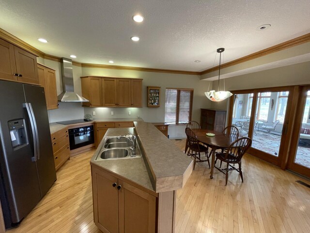 164 Invitational Dr, Gaylord, MI 49735 - kitchen with black appliances, wall chimney exhaust hood, crown molding, a kitchen island with sink, and light wood finished floors