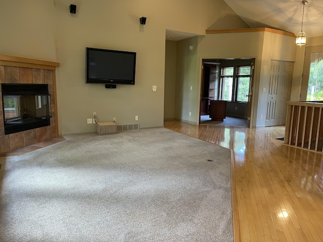 164 Invitational Dr, Gaylord, MI 49735 - unfurnished living room featuring healthy amount of natural light, hardwood / wood-style flooring, a tile fireplace, and high vaulted ceiling