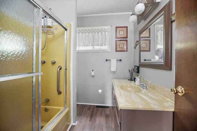 2040 Mary Anne Dr, Lewiston, MI 49756 - full bath with wood finished floors, vanity, shower / bath combination with glass door, ornamental molding, and a textured ceiling