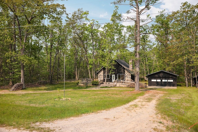 2040 Mary Anne Dr, Lewiston, MI 49756 - view of front of house with dirt driveway, stone siding, an outbuilding, a detached garage, and a front yard