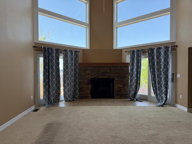 13551 US-23, Cheboygan, MI 49721 - unfurnished living room featuring a towering ceiling, a fireplace, carpet, and tile patterned floors