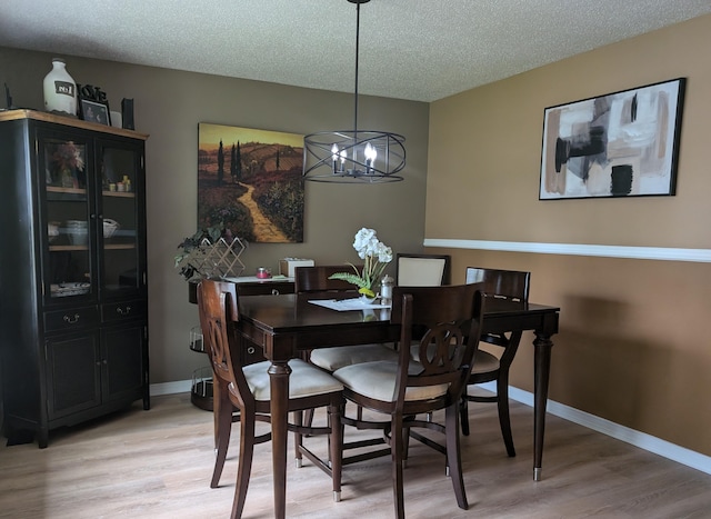 101 Island View Dr, Alpena, MI 49707 - dining room featuring a chandelier, light wood finished floors, a textured ceiling, and baseboards