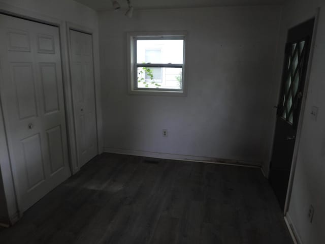 120 Copier St, Cadillac, MI 49601 - unfurnished bedroom featuring dark wood finished floors, rail lighting, and baseboards