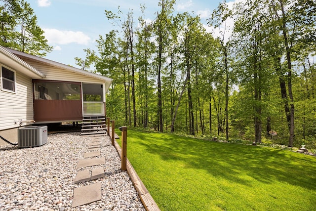 2510 Primrose Rd, Elmira, MI 49730 - view of grassy yard featuring a sunroom and central AC unit