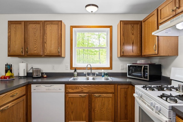 2510 Primrose Rd, Elmira, MI 49730 - kitchen with white appliances, a sink, under cabinet range hood, brown cabinetry, and dark countertops