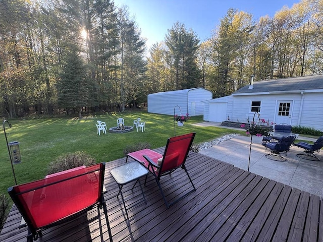 2056 Hobbs Dr, Alpena, MI 49707 - wooden deck with a fire pit, a patio, a lawn, and an outbuilding