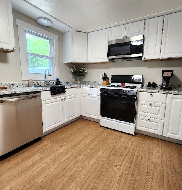 2056 Hobbs Dr, Alpena, MI 49707 - kitchen featuring stainless steel appliances, light wood-type flooring, white cabinetry, a sink, and light stone counters