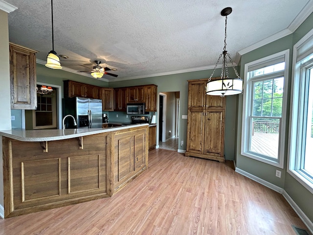 N1746 Smith Rd, Saint Ignace, MI 49781 - kitchen featuring appliances with stainless steel finishes, a peninsula, light wood-style flooring, crown molding, and light countertops