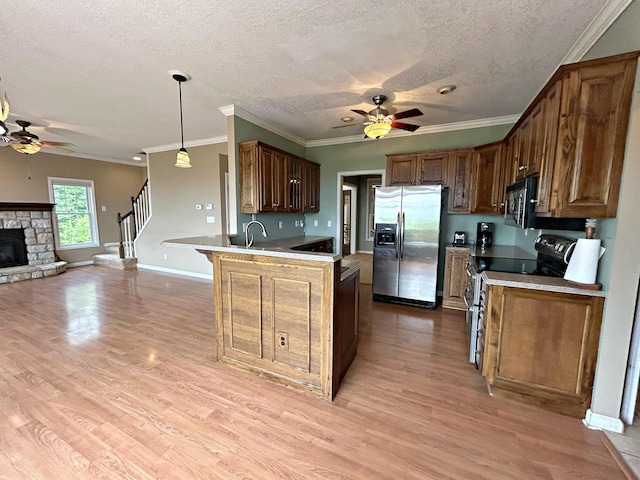 N1746 Smith Rd, Saint Ignace, MI 49781 - kitchen with stainless steel appliances, ceiling fan, open floor plan, a peninsula, and light wood finished floors