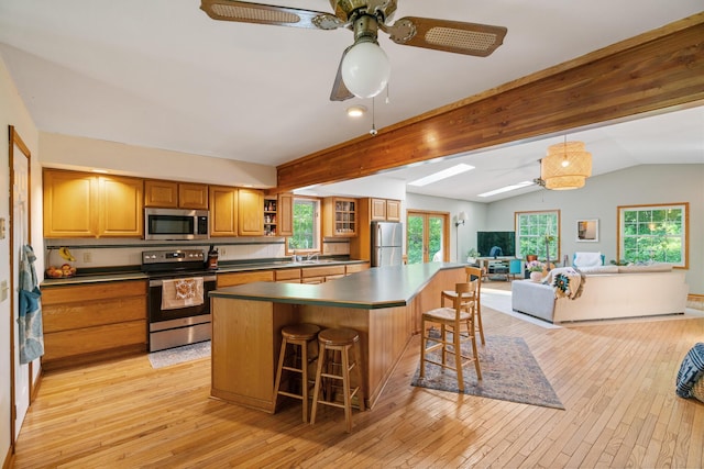 9707 Rogers Rd, Alanson, MI 49706 - kitchen with appliances with stainless steel finishes, ceiling fan, open floor plan, a breakfast bar area, and brown cabinets