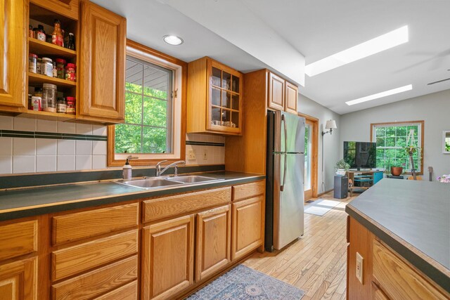 9707 Rogers Rd, Alanson, MI 49706 - kitchen with freestanding refrigerator, a sink, dark countertops, decorative backsplash, and plenty of natural light