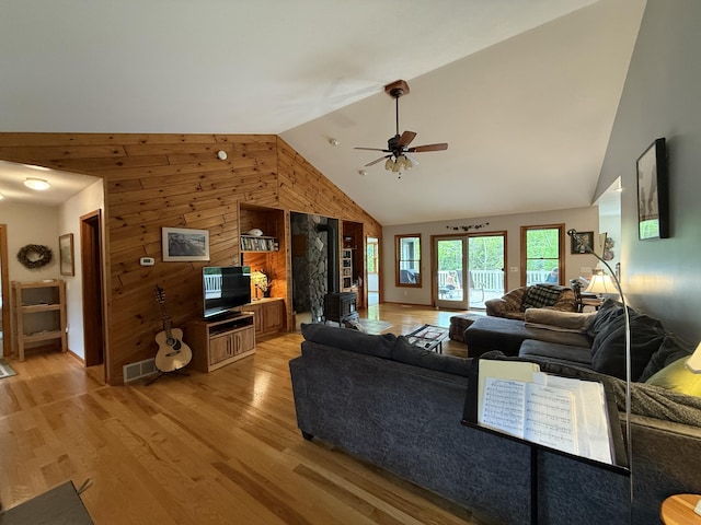 1058 Marlas Way, Cheboygan, MI 49721 - living room featuring light wood-style flooring, high vaulted ceiling, wooden walls, and a ceiling fan