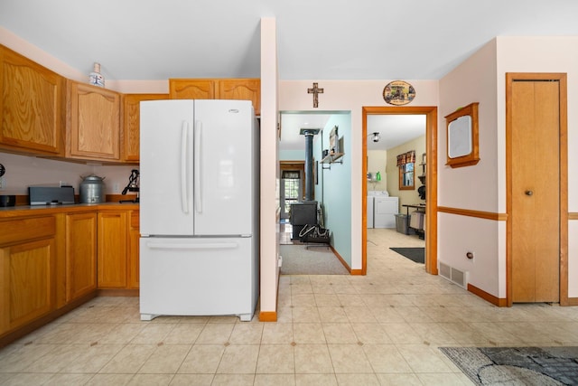 5918 Neumann Rd, Lewiston, MI 49756 - kitchen with freestanding refrigerator, washer / dryer, baseboards, a wood stove, and brown cabinets
