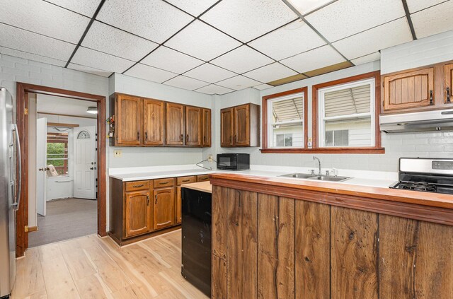 211 S Birney St, Bay City, MI 48708 - kitchen featuring under cabinet range hood, appliances with stainless steel finishes, a sink, light wood finished floors, and a drop ceiling