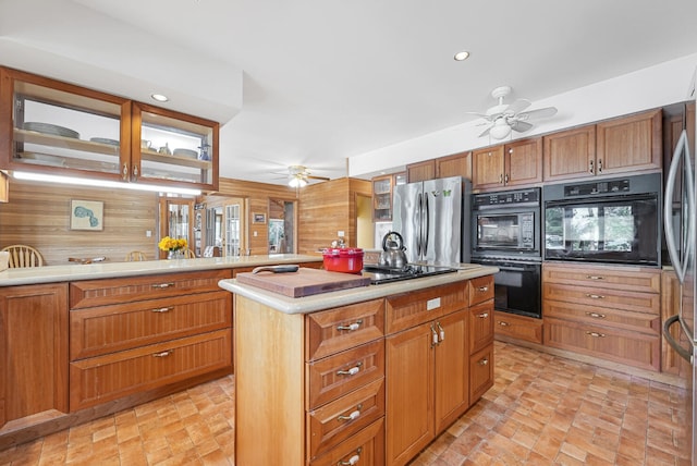 117 Timber Trl, Roscommon, MI 48653 - kitchen with a ceiling fan, freestanding refrigerator, wood walls, light countertops, and a center island