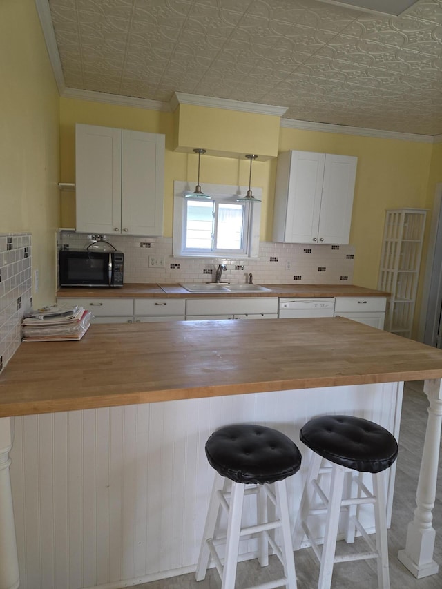 208 S S D St, Cheboygan, MI 49721 - kitchen featuring wood counters, black microwave, a sink, tasteful backsplash, and an ornate ceiling