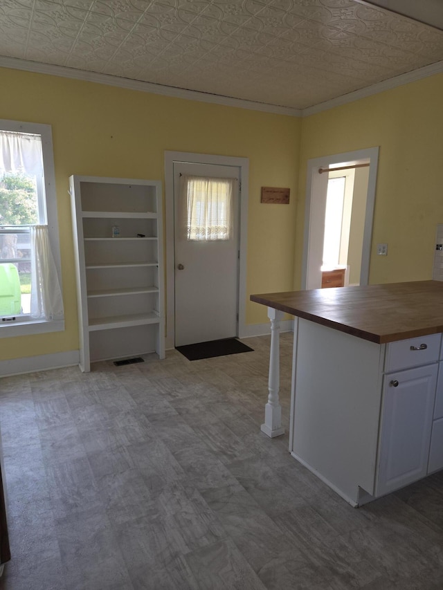 208 S S D St, Cheboygan, MI 49721 - kitchen featuring butcher block countertops, ornamental molding, healthy amount of natural light, an ornate ceiling, and white cabinetry