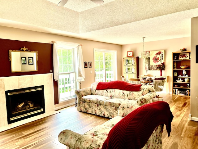 1745 Mullett Lake Woods Rd, Cheboygan, MI 49721 - living room with wood-type flooring, a fireplace, a textured ceiling, and a ceiling fan