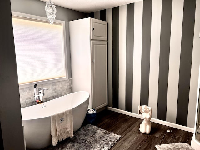 1745 Mullett Lake Woods Rd, Cheboygan, MI 49721 - bathroom with a freestanding bath, wood finished floors, baseboards, wallpapered walls, and a chandelier