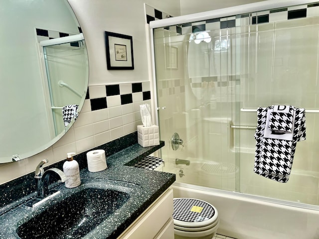 1745 Mullett Lake Woods Rd, Cheboygan, MI 49721 - bathroom featuring vanity, tile walls, shower / bath combination with glass door, tasteful backsplash, and toilet