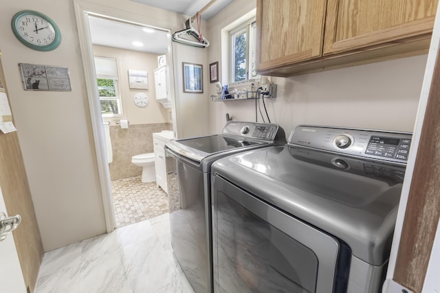 217 Cherry St, Houghton Lake, MI 48629 - washroom with washing machine and clothes dryer, tile walls, a wainscoted wall, and cabinet space