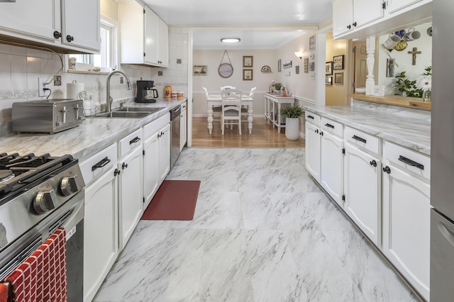 217 Cherry St, Houghton Lake, MI 48629 - kitchen featuring appliances with stainless steel finishes, white cabinetry, decorative backsplash, light stone countertops, and crown molding