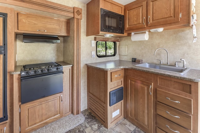 217 Cherry St, Houghton Lake, MI 48629 - kitchen with black microwave, under cabinet range hood, range with gas stovetop, and brown cabinetry