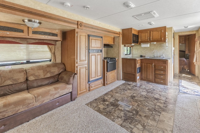 217 Cherry St, Houghton Lake, MI 48629 - kitchen with brown cabinets, black microwave, light countertops, open floor plan, and stone finish flooring