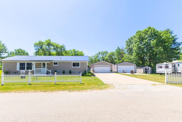 217 Cherry St, Houghton Lake, MI 48629 - view of front of home with an outbuilding, a fenced front yard, a detached garage, and a metal roof