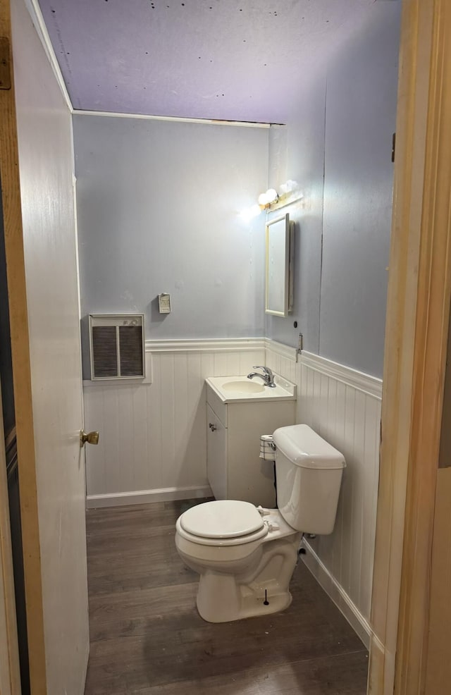 3134 Kneeland St, Lewiston, MI 49756 - half bathroom featuring wood finished floors, toilet, a wainscoted wall, vanity, and an AC wall unit
