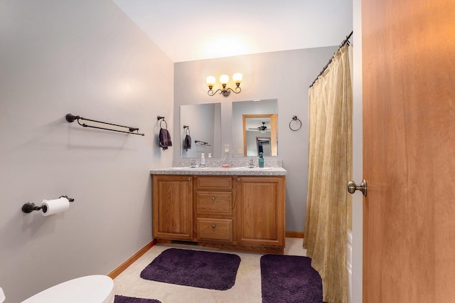 10702 Southwood Dr, Mancelona, MI 49659 - bathroom featuring toilet, double vanity, lofted ceiling, and baseboards