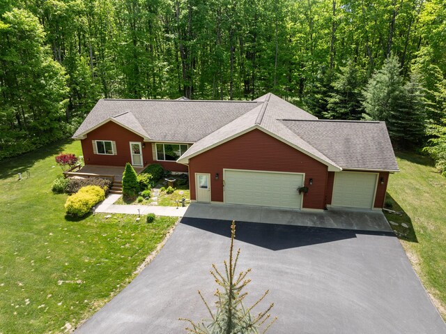 11193 Hassler Woods Trl, Alanson, MI 49706 - single story home featuring driveway, a front yard, a garage, roof with shingles, and a view of trees