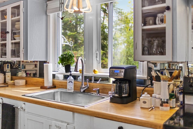 7106 Douglas Lake Rd, Johannesburg, MI 49751 - kitchen featuring a sink, glass insert cabinets, white cabinets, light countertops, and a chandelier