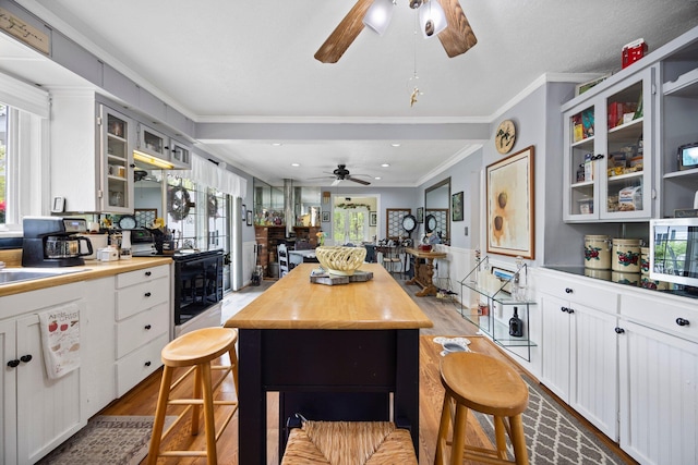 7106 Douglas Lake Rd, Johannesburg, MI 49751 - kitchen with a ceiling fan, electric range, ornamental molding, stainless steel microwave, and a center island