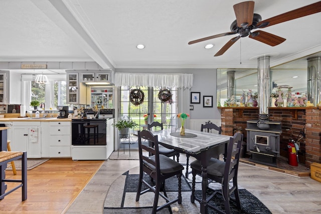 7106 Douglas Lake Rd, Johannesburg, MI 49751 - dining area with a wood stove, ceiling fan, healthy amount of natural light, ornamental molding, and light wood-style flooring