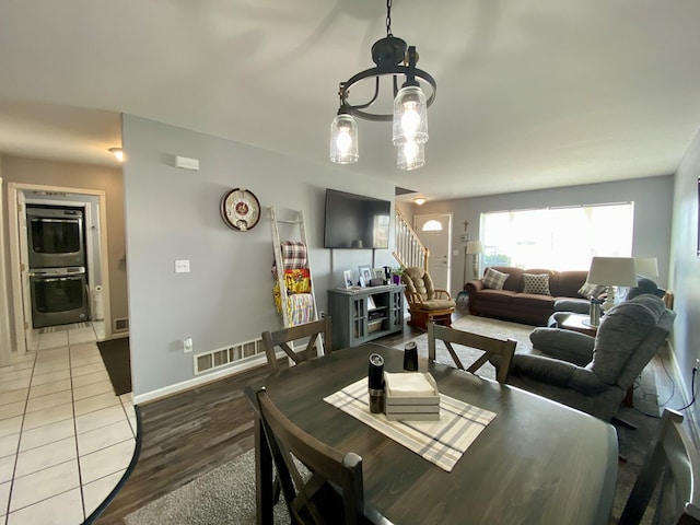 2476 W Branch Dr, West Branch, MI 48661 - dining space featuring stairs, wood finished floors, baseboards, and a chandelier