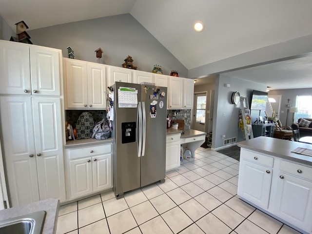 2476 W Branch Dr, West Branch, MI 48661 - kitchen with stainless steel fridge with ice dispenser, decorative backsplash, white cabinetry, light tile patterned flooring, and open floor plan