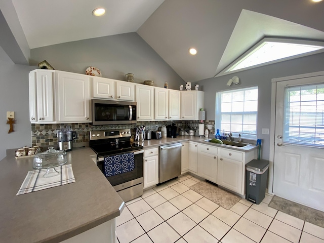 2476 W Branch Dr, West Branch, MI 48661 - kitchen featuring stainless steel appliances, a sink, vaulted ceiling, tasteful backsplash, and white cabinetry