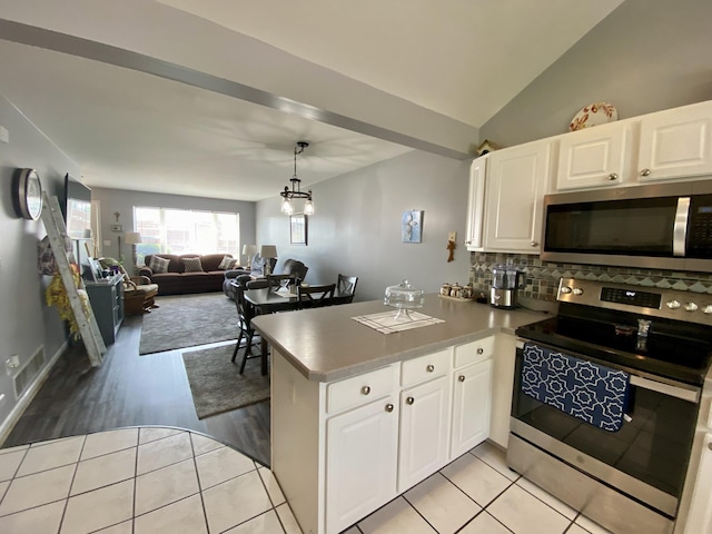2476 W Branch Dr, West Branch, MI 48661 - kitchen with stainless steel appliances, a peninsula, white cabinetry, tasteful backsplash, and vaulted ceiling