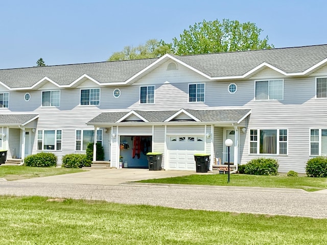 2476 W Branch Dr, West Branch, MI 48661 - multi unit property featuring an attached garage, concrete driveway, a front yard, and a shingled roof