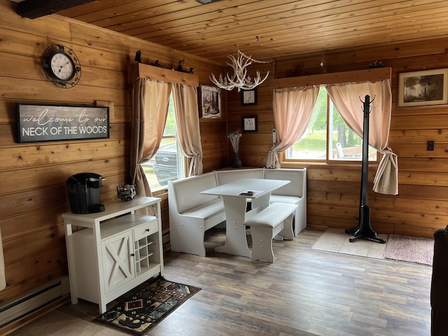 7781 N M-18, Roscommon, MI 48653 - dining area featuring baseboard heating, wood ceiling, a chandelier, wood walls, and light wood-style flooring