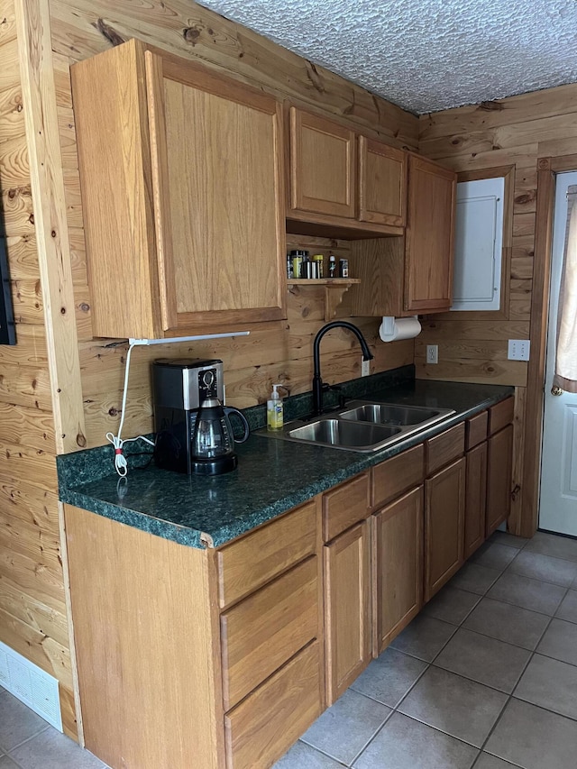 7781 N M-18, Roscommon, MI 48653 - kitchen with a sink, light tile patterned floors, dark countertops, wooden walls, and a textured ceiling