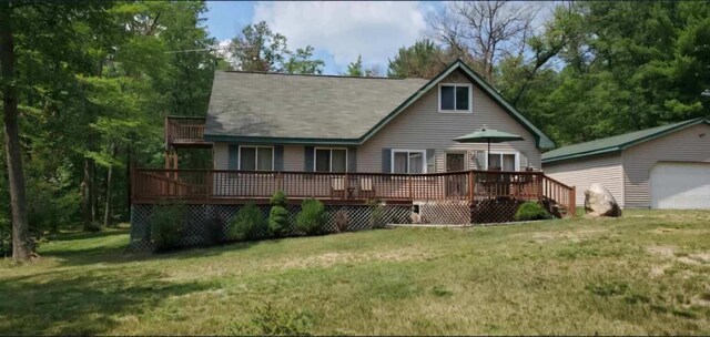 7781 N M-18, Roscommon, MI 48653 - back of house featuring a deck, a lawn, a detached garage, and an outbuilding