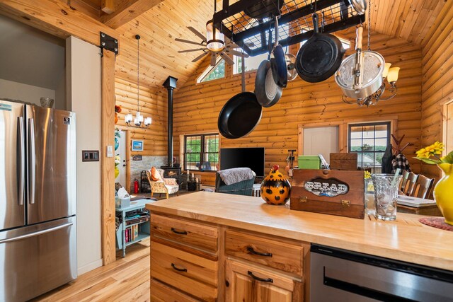 8406 S Shire Rd, Vanderbilt, MI 49795 - kitchen featuring stainless steel appliances, wood counters, rustic walls, a wood stove, and high vaulted ceiling