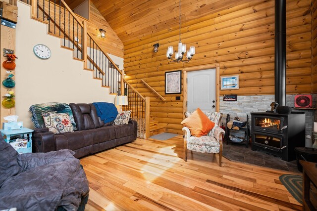 8406 S Shire Rd, Vanderbilt, MI 49795 - living room with stairway, high vaulted ceiling, log walls, a wood stove, and hardwood / wood-style flooring